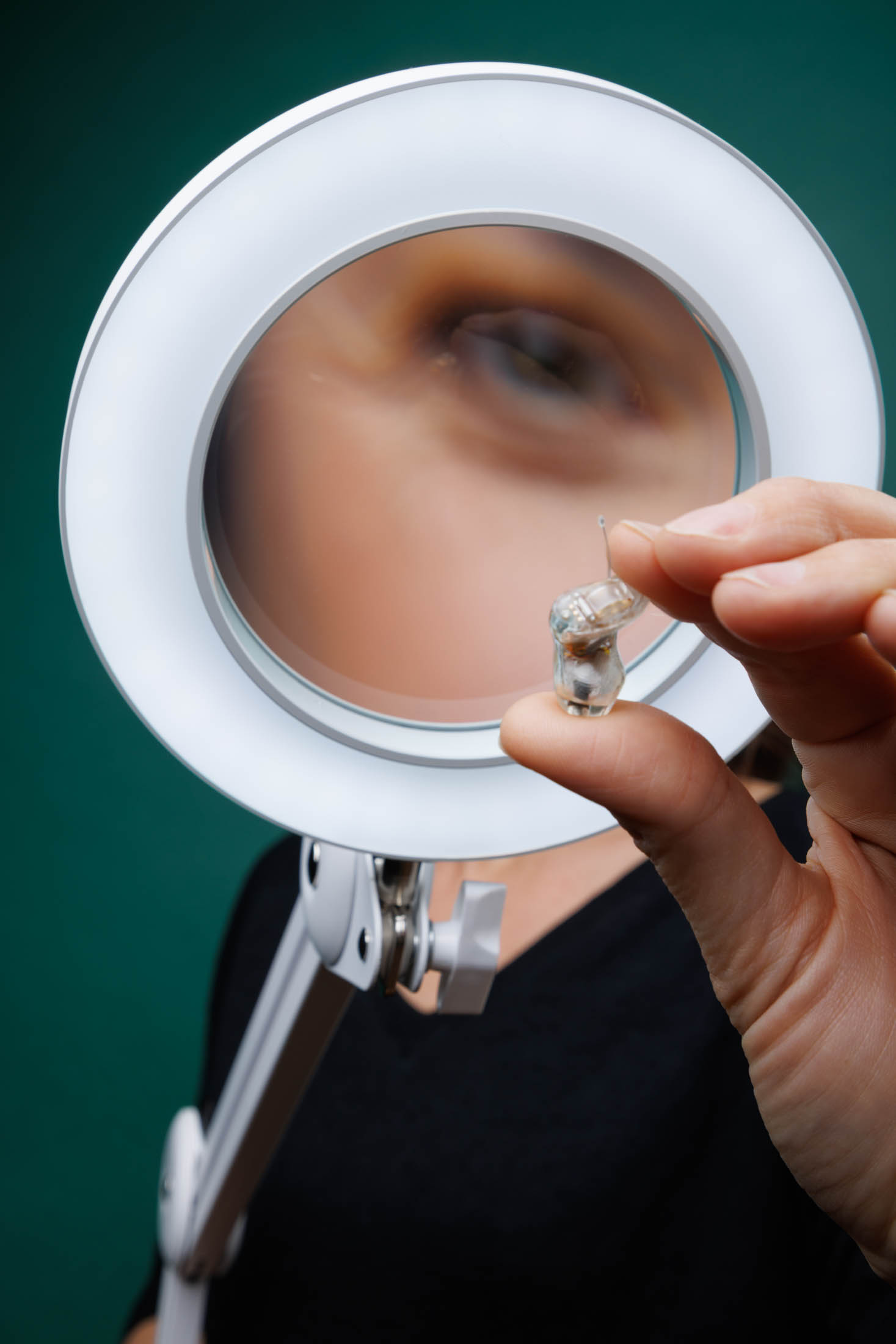 Contrôle d’un appareil auditif sous lampe-loupe — Dyapason, photo David Morganti