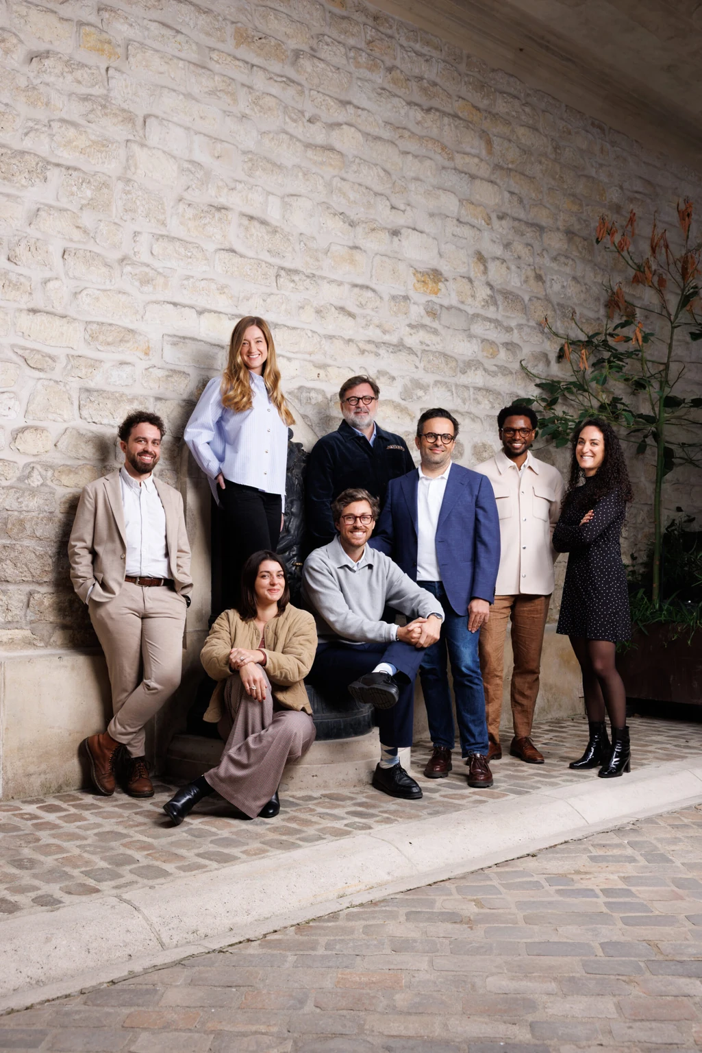 Les huit associés et collaborateurs du cabinet Greenwich Avocats dans une cour pavée, devant un mur de pierre — photo David Morganti