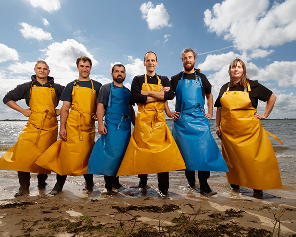 Photo de 6 eleveurs de saumons au bord de l'eau sur une plage